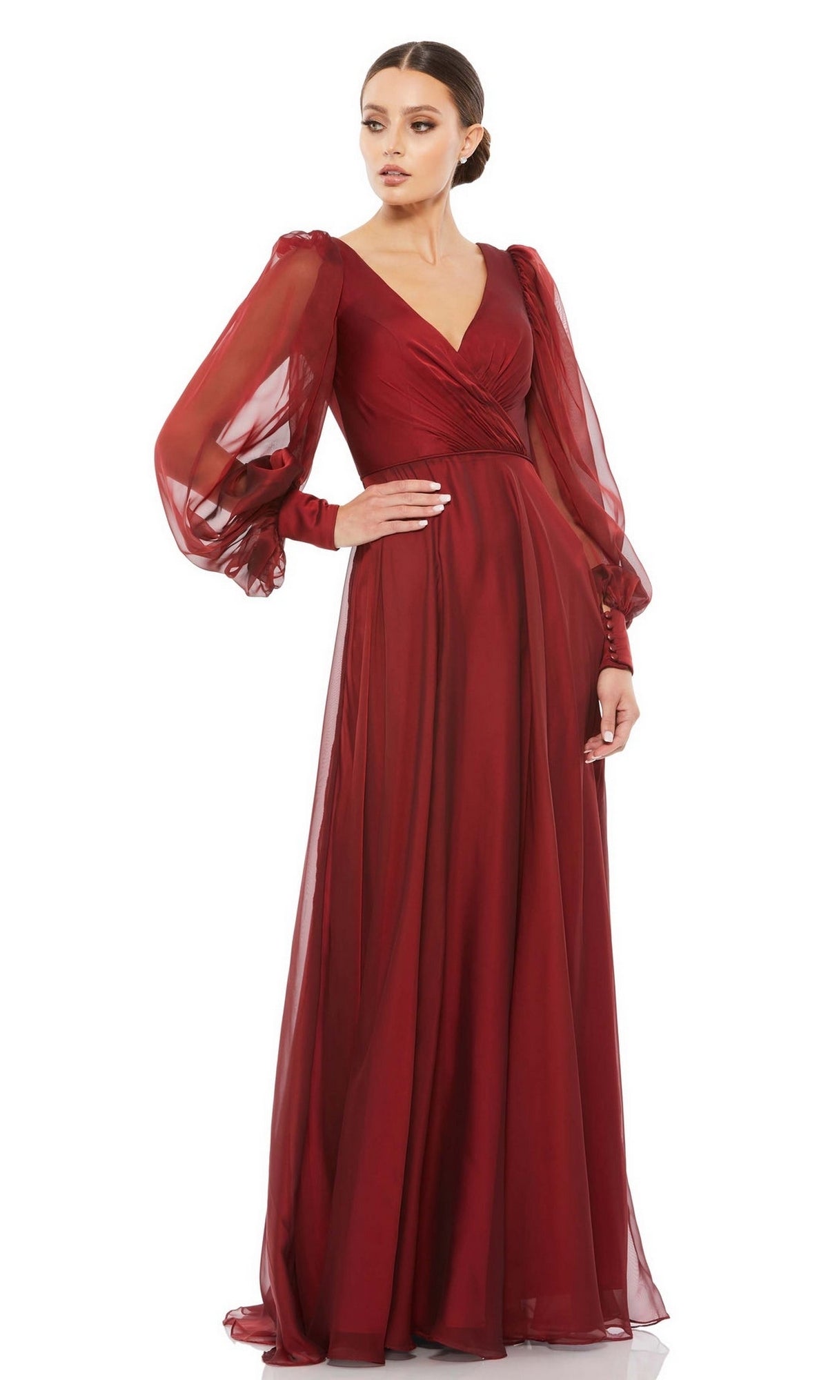 A woman models the Mac Duggal 67873 Long Sleeve Long Red Formal Gown—floor-length with sheer puffed sleeves, V-neckline, and fitted waist—ideal as a mother of the bride dress, posed against a white background.